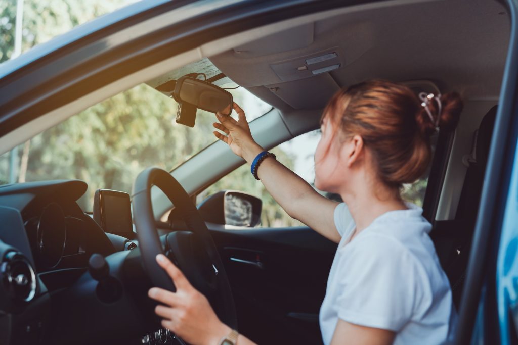 Young female driver in a white t-shirt checking her mirror before driving off.