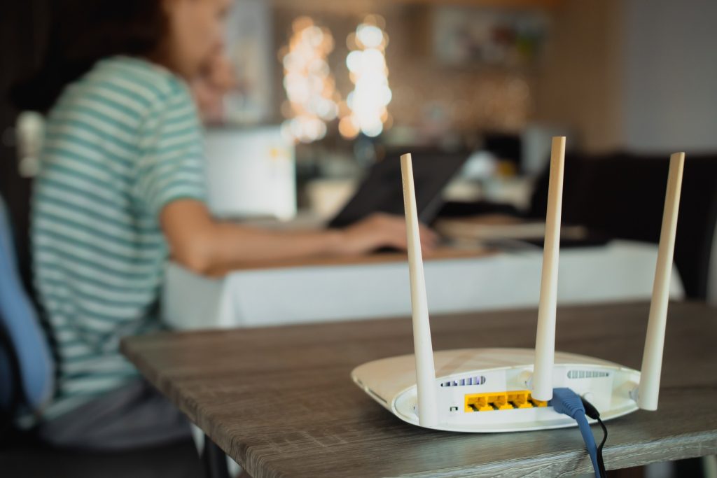 An internal shot of a home with a broadband device visible in the foreground and people working away on laptops in the background.