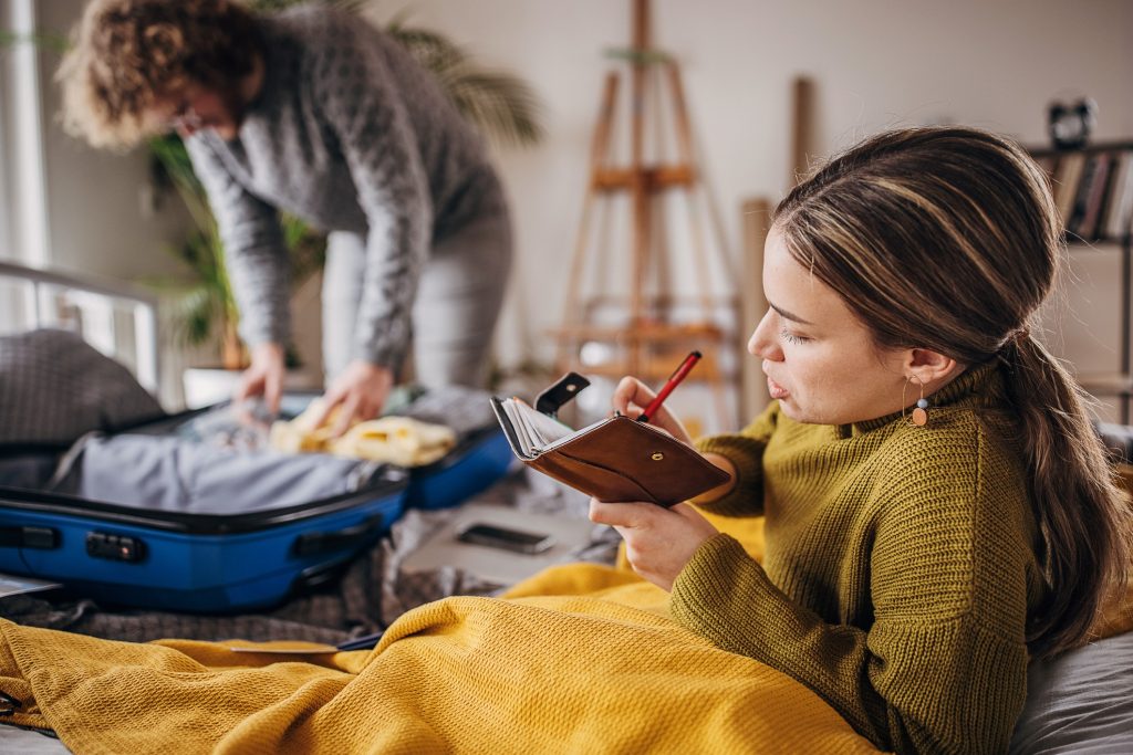 A couple pictured packing for their holidays, a suitcase and a checklist visible.