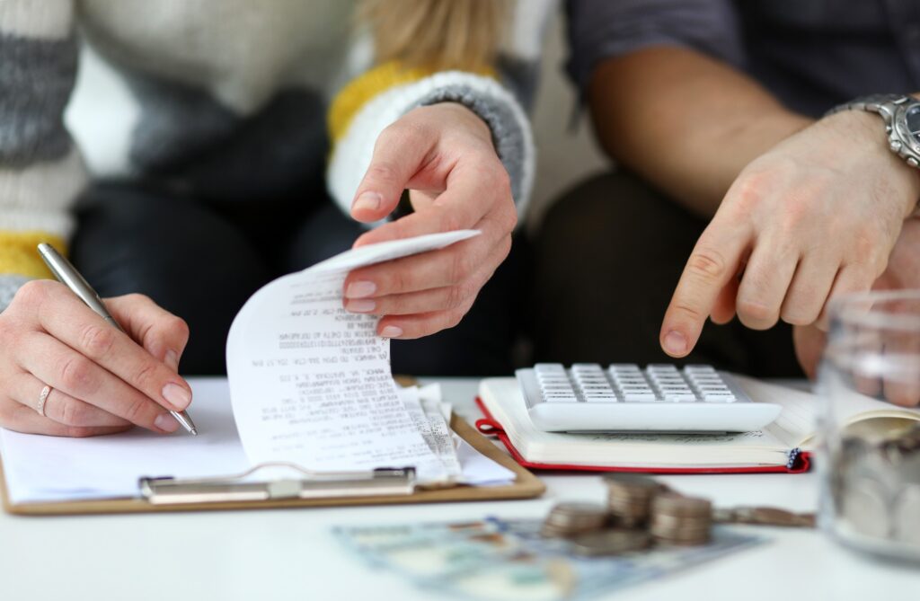 A couple review their finances - money, receipts and a calculator visible.