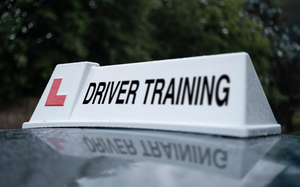 A car with a large driver training sign on the roof.